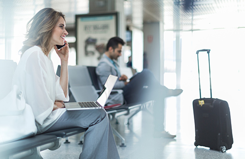 Woman sitting at the airport talking on the phone, corporate travel