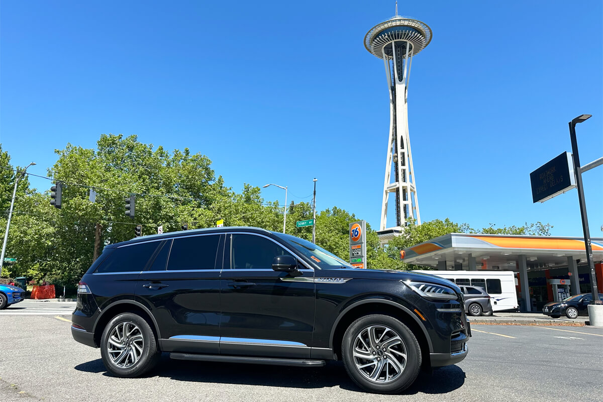 Starline's Black Lincoln Aviator driving in Seattle with Space Needle visible in the background