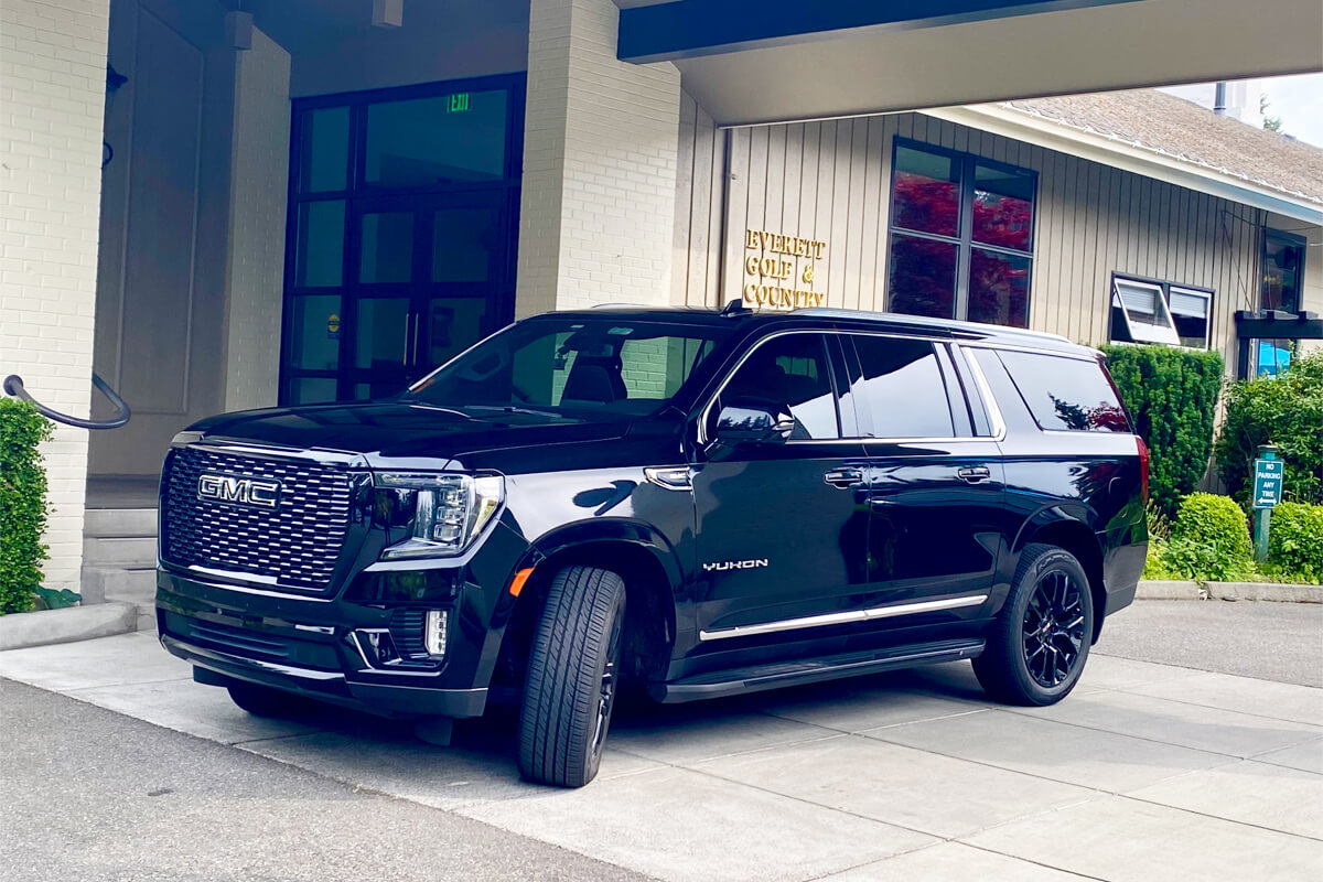 Starline's black GMC Yukon SUV picking up a passenger from front entrance of the Everett Golf & Country Club