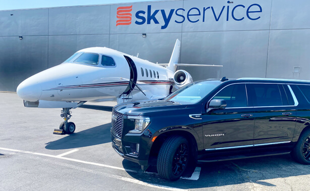 Black GMC Yukon from a Seattle corporate & executive car service waiting beside a private jet at the Skyservice hangar for seamless VIP airport transfer