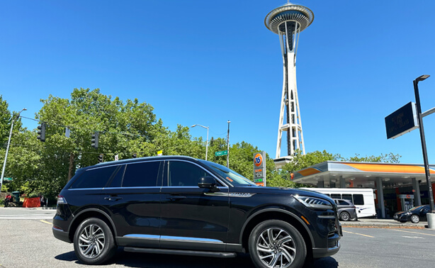 Starline's black luxury SUV carrying guests on a private Seattle city tour, cruising past the Space Needle.