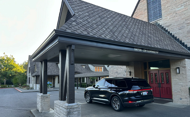Starline’s black luxury SUV positioned discreetly under a church portico, providing dignified Seattle funeral limo service for grieving families.