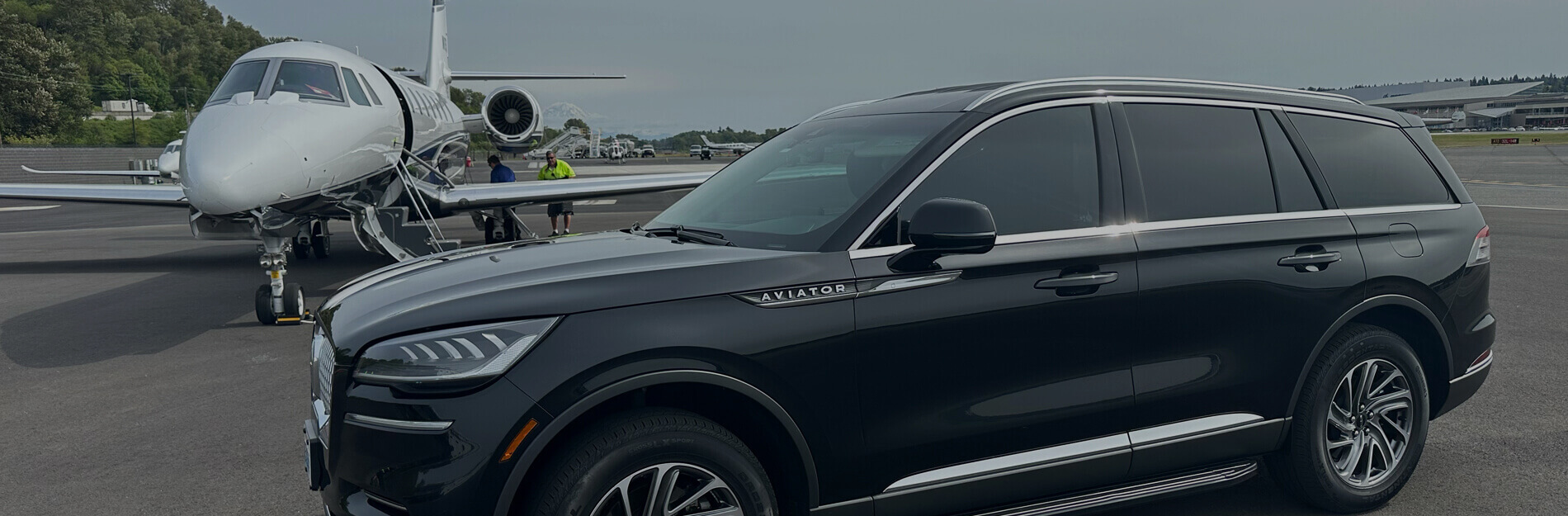Black Lincoln Aviator parked beside a private jet at a Seattle airfield, representing Starline’s premium black car and chauffeur service.