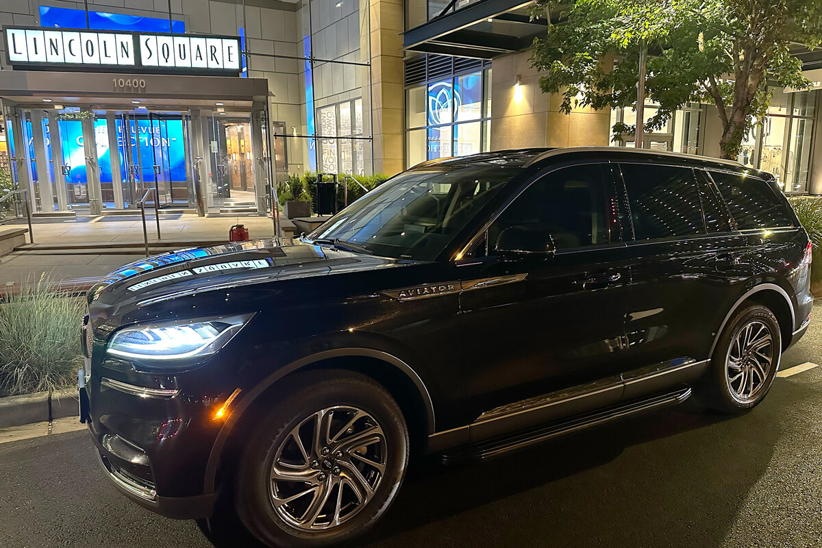 Black chauffeur SUV parked outside Lincoln Square in downtown Bellevue for airport and event transportation