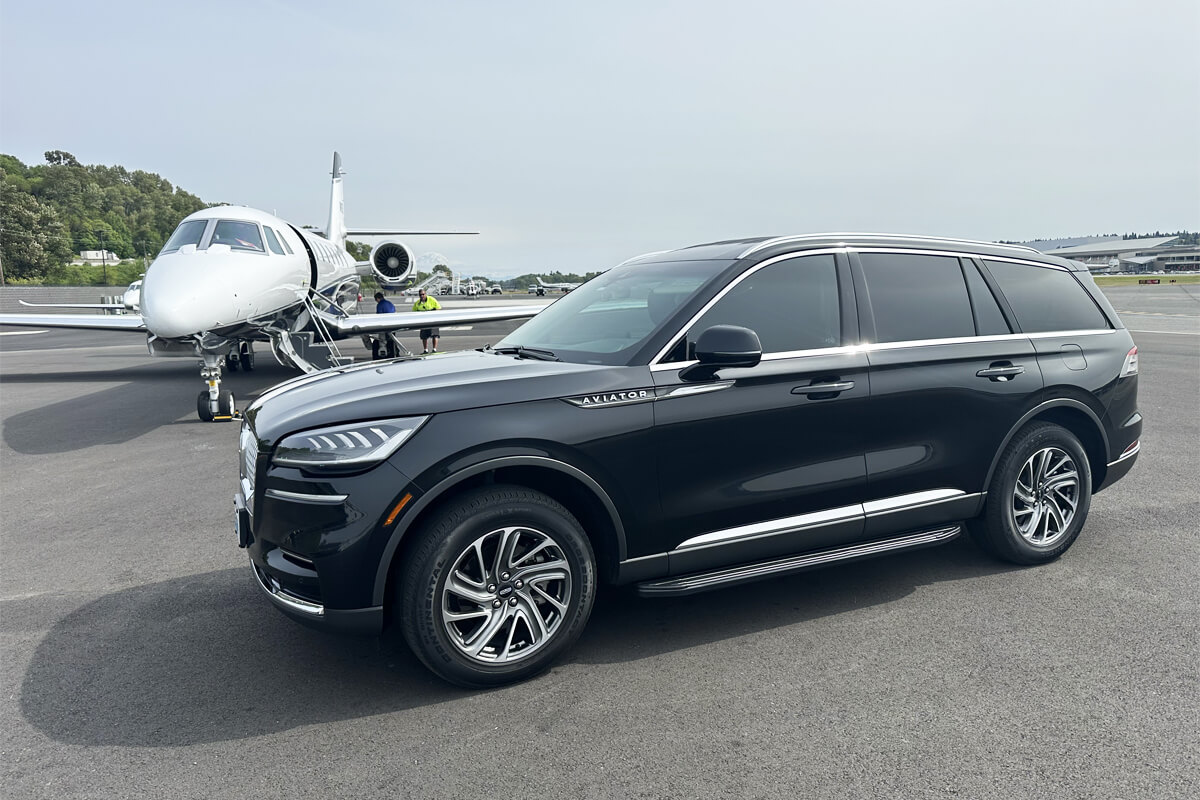 Starline's luxury black SUV parked beside a private jet on the tarmac, representing seamless executive airport transportation.