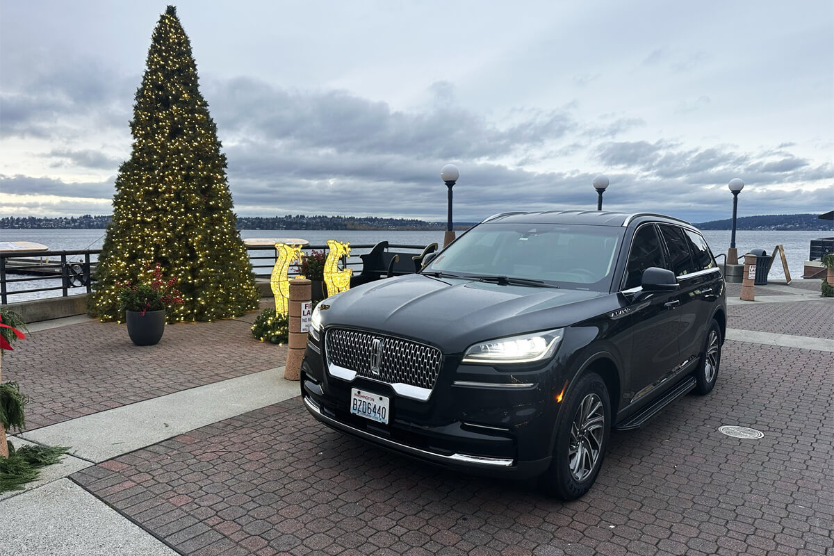 Lincoln Aviator SUV near a decorated Christmas tree at the waterfront on a cloudy winter day in Seattle area.