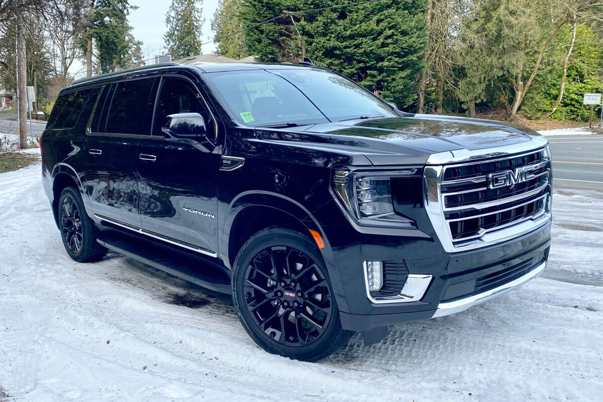 Starline's black GMC Yukon full-size SUV with 4-wheel drive and snow tires parked on a snowy Seattle road for winter chauffeur service.