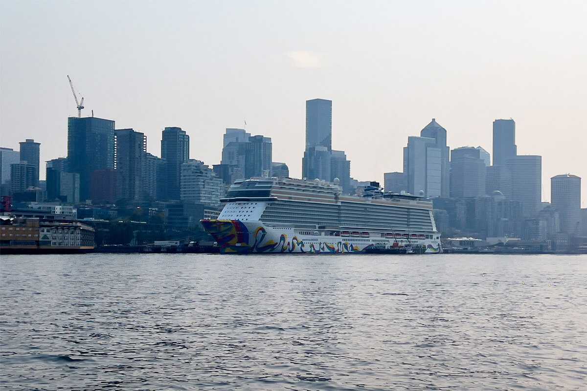 Cruise ship on Elliott Bay with the Seattle skyline behind it, viewed from the water.
