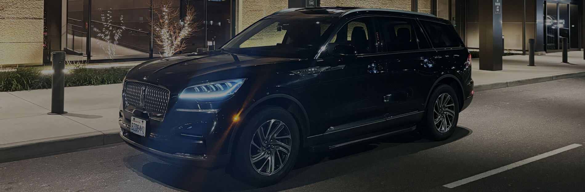 Luxury black SUV from Starline Town Car & Limousine Service waiting at a Seattle area airport at night