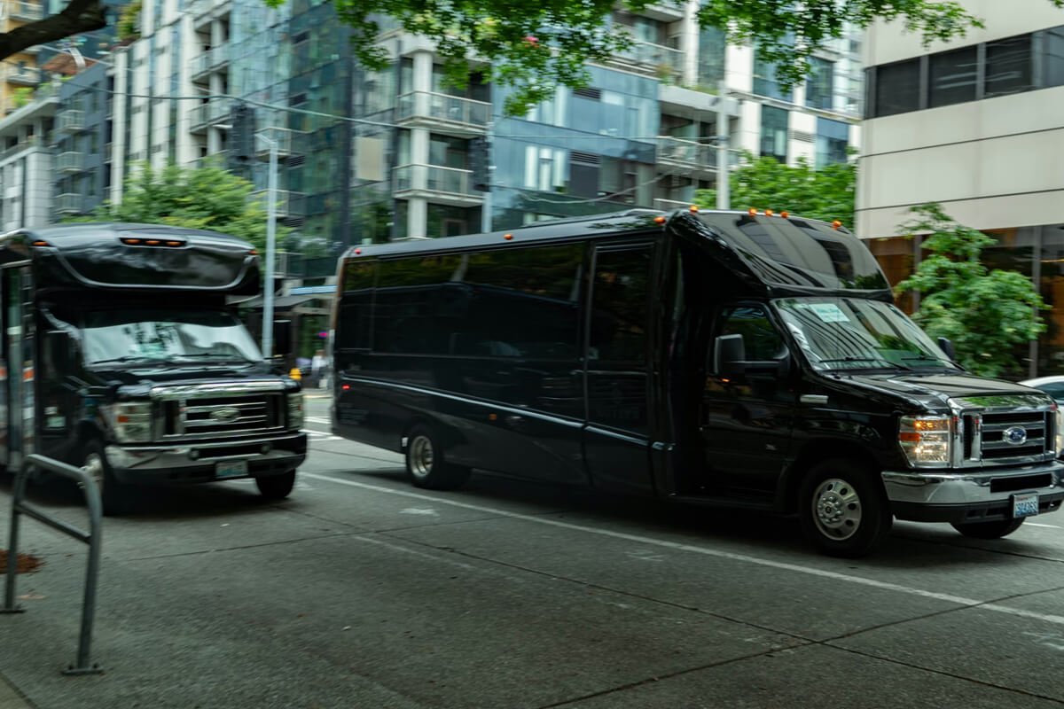 Two black shared airport shuttle vans driving in downtown Seattle