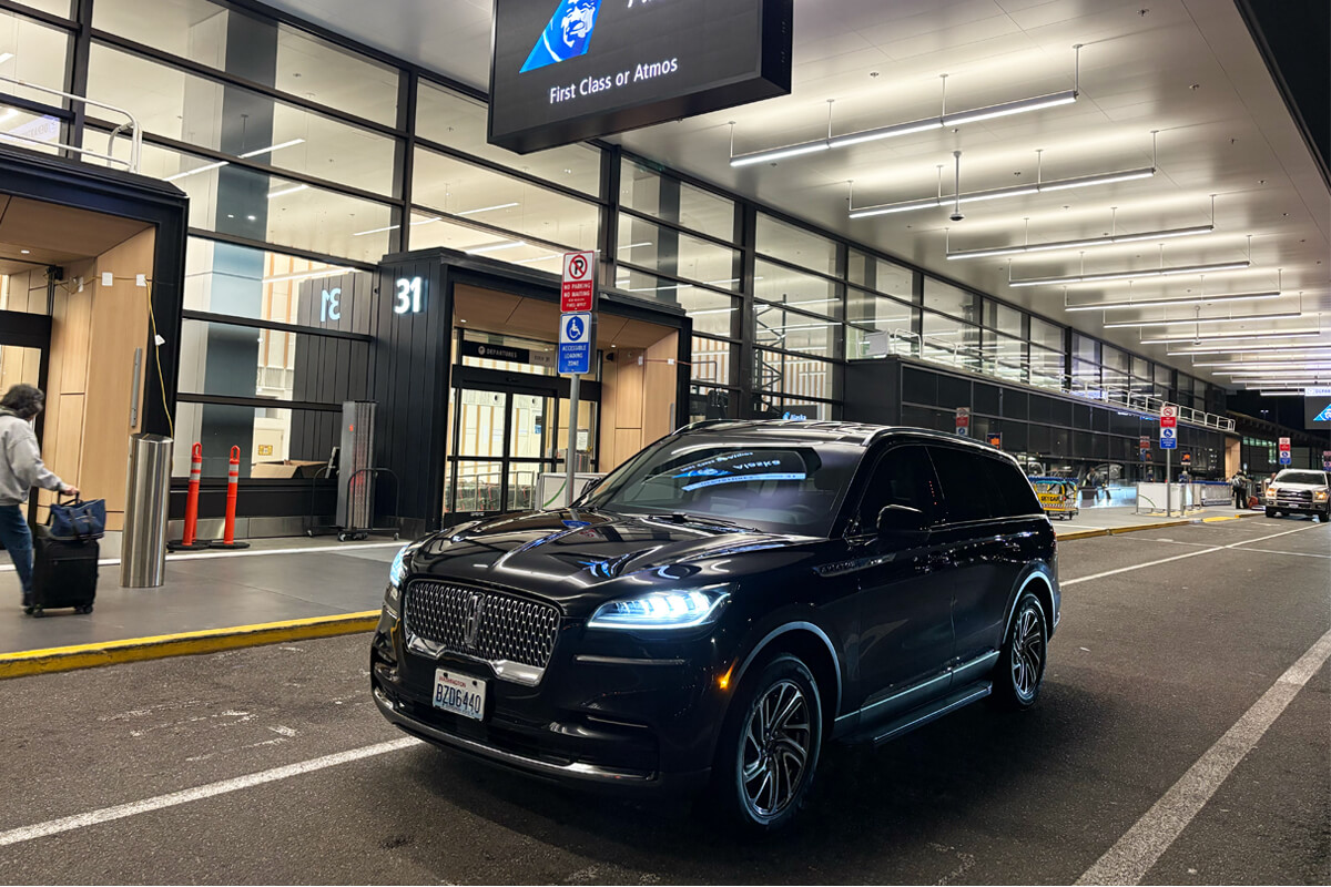 Black Lincoln SUV at Seattle-Tacoma International Airport curbside pickup area for private Bellevue airport transportation.