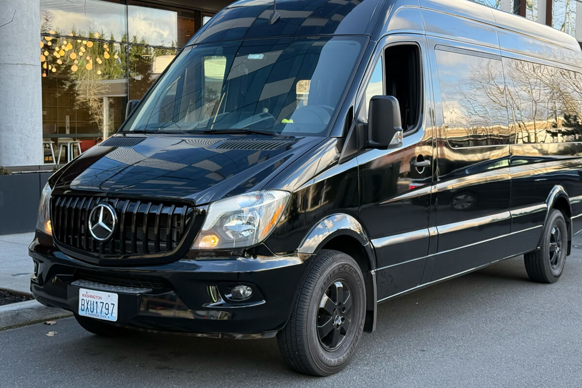 Black Mercedes Sprinter Van parked outside a modern building for group transportation service in the Bellingham area.