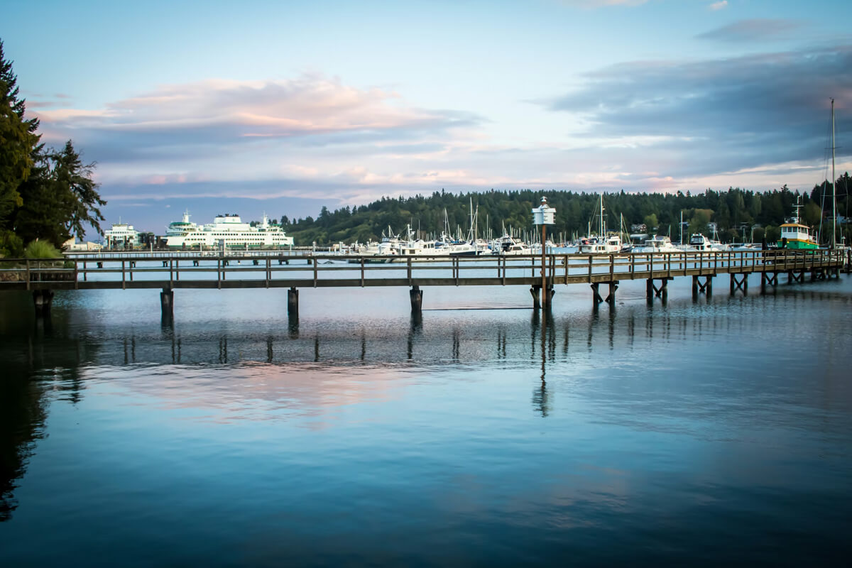 Bainbridge Island ferry terminal and marina at sunset with calm waterfront and moored boats near Seattle.