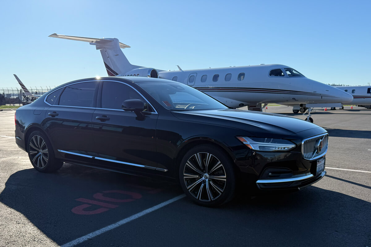 Black Volvo executive sedan parked beside a private jet for Mercer Island private aviation and FBO transportation