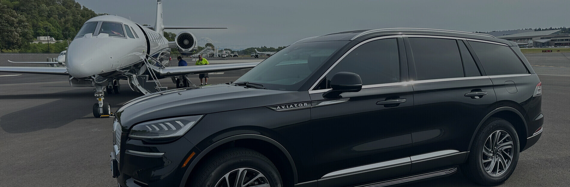Black Lincoln Aviator parked beside a private jet at a Seattle airfield, representing Starline’s premium black car and chauffeur service.