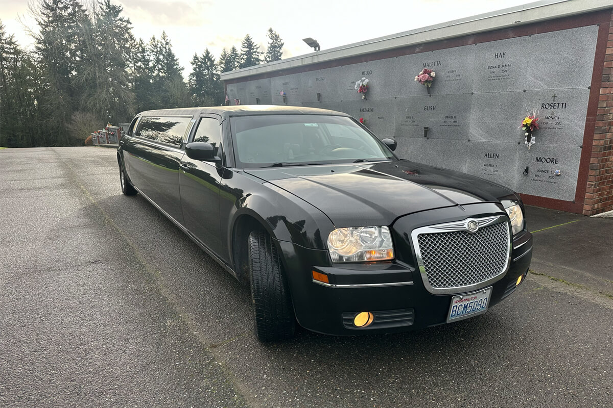 Black stretch limousine parked at a cemetery mausoleum for funeral transportation service in Seattle