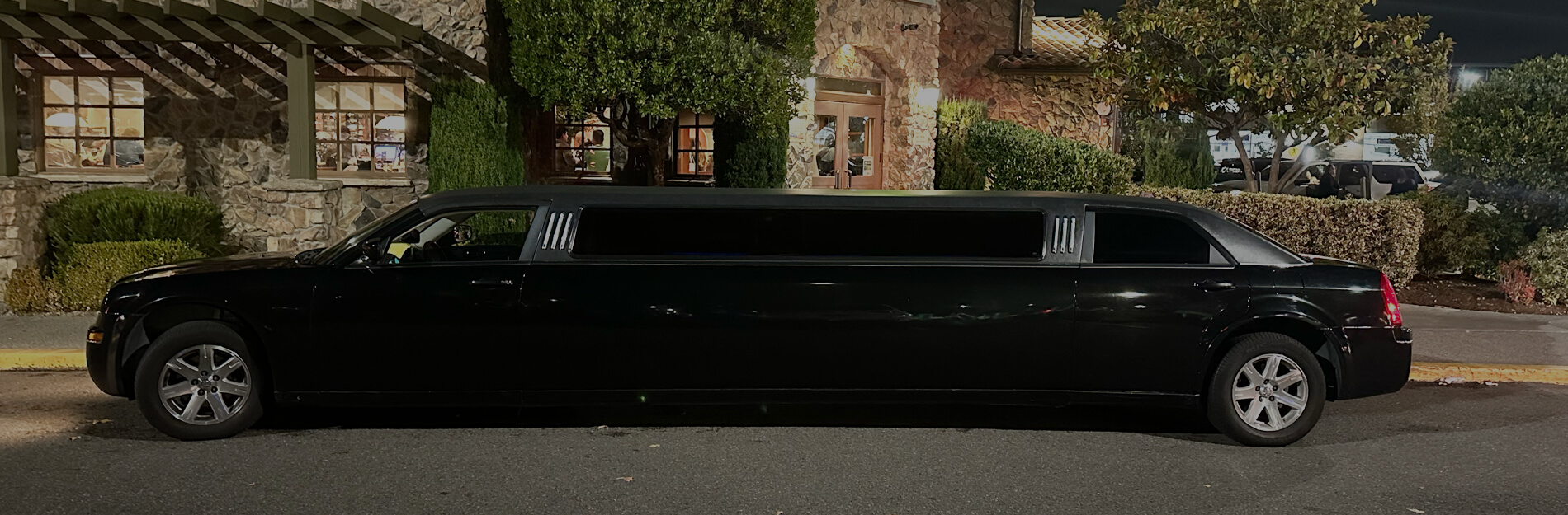 Black stretch limousine parked outside a Seattle event venue at night for private event transportation and special occasion limo service.