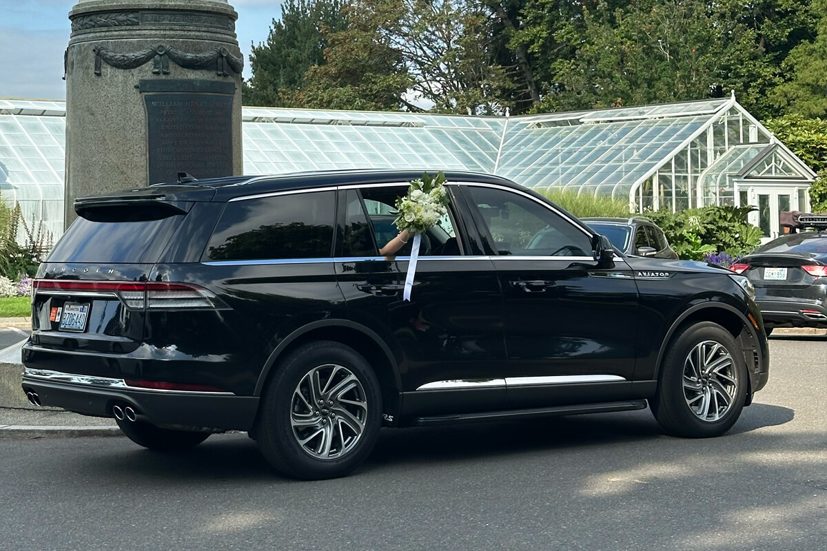 Black SUV arriving at a Seattle wedding venue, with bridal flowers visible from the window for private event and wedding chauffeur service.