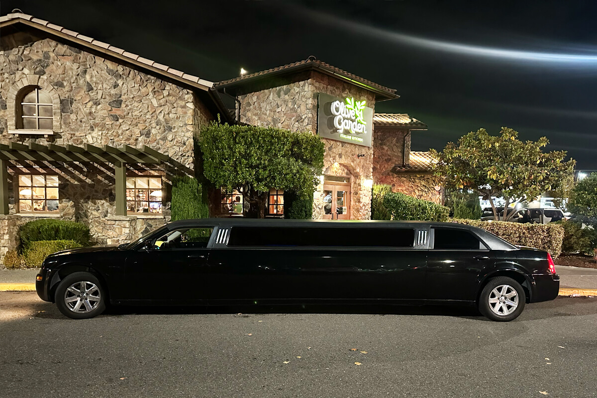 Black stretch limousine parked outside a Seattle restaurant at night for private event transportation, dinner outings, and special occasion limo service.