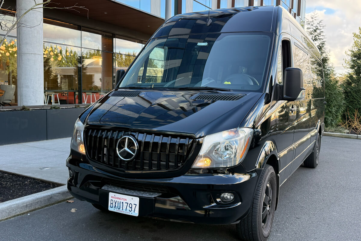 Black Mercedes Sprinter Van parked outside a winery building for group wine tour transportation