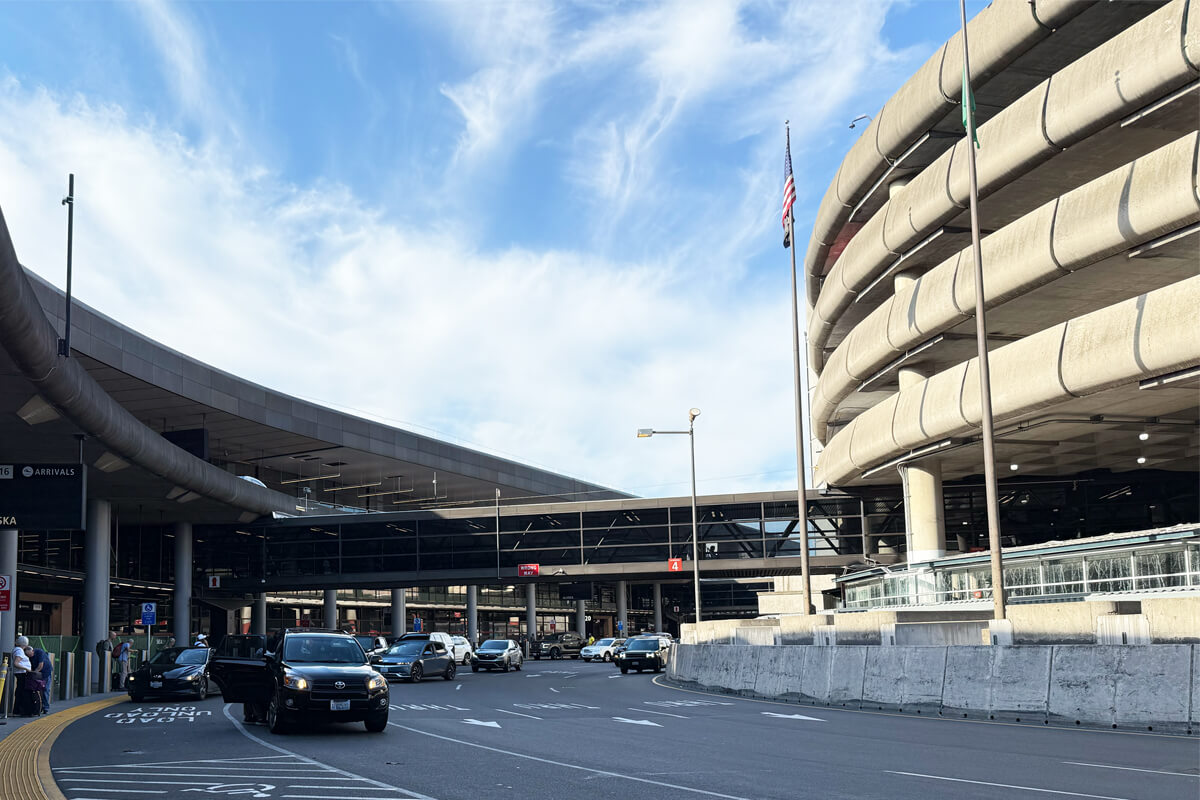 SeaTac arrivals curb with terminal and parking garage in view