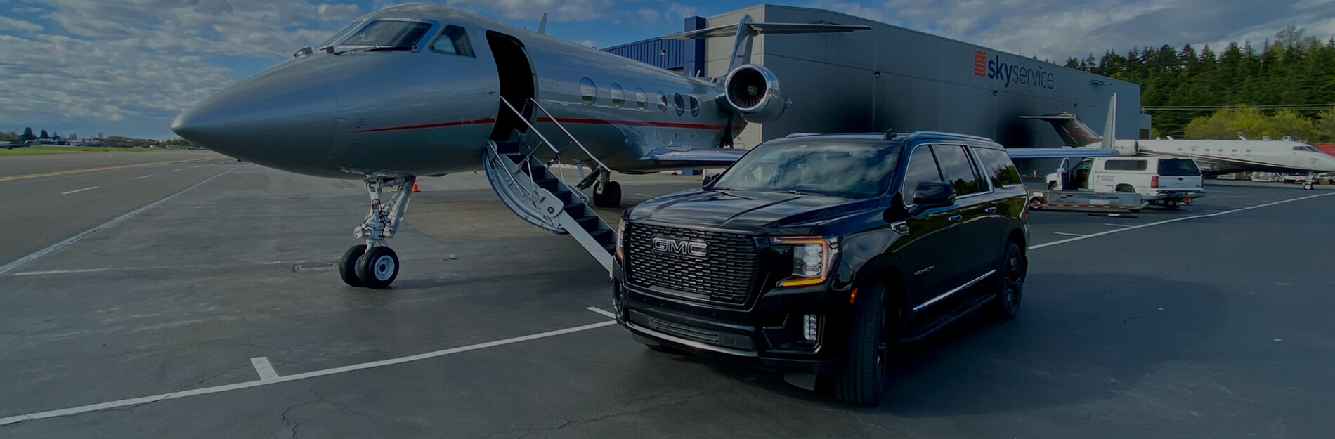 Black GMC SUV beside a private jet at Skyservice in Seattle for private aviation ground transportation
