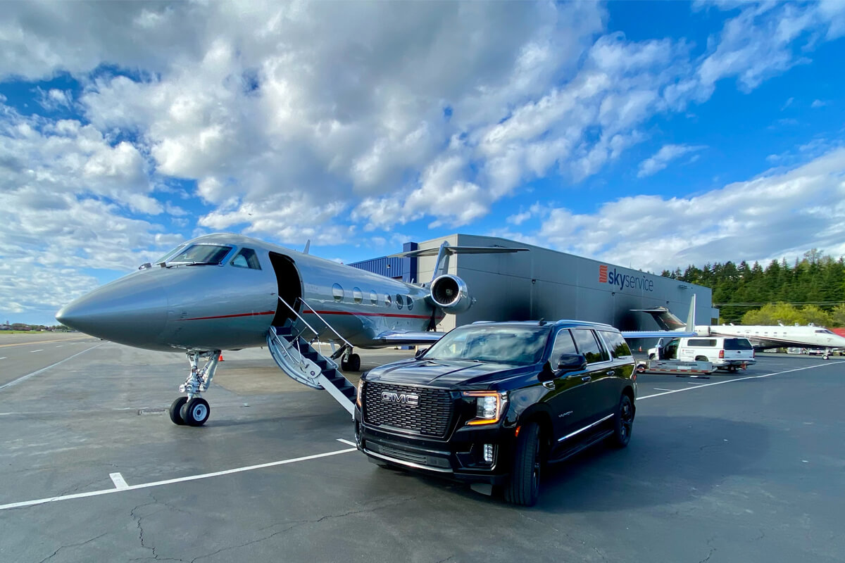 Black GMC SUV beside a private jet on the tarmac at Skyservice in Seattle for private aviation ground transportation