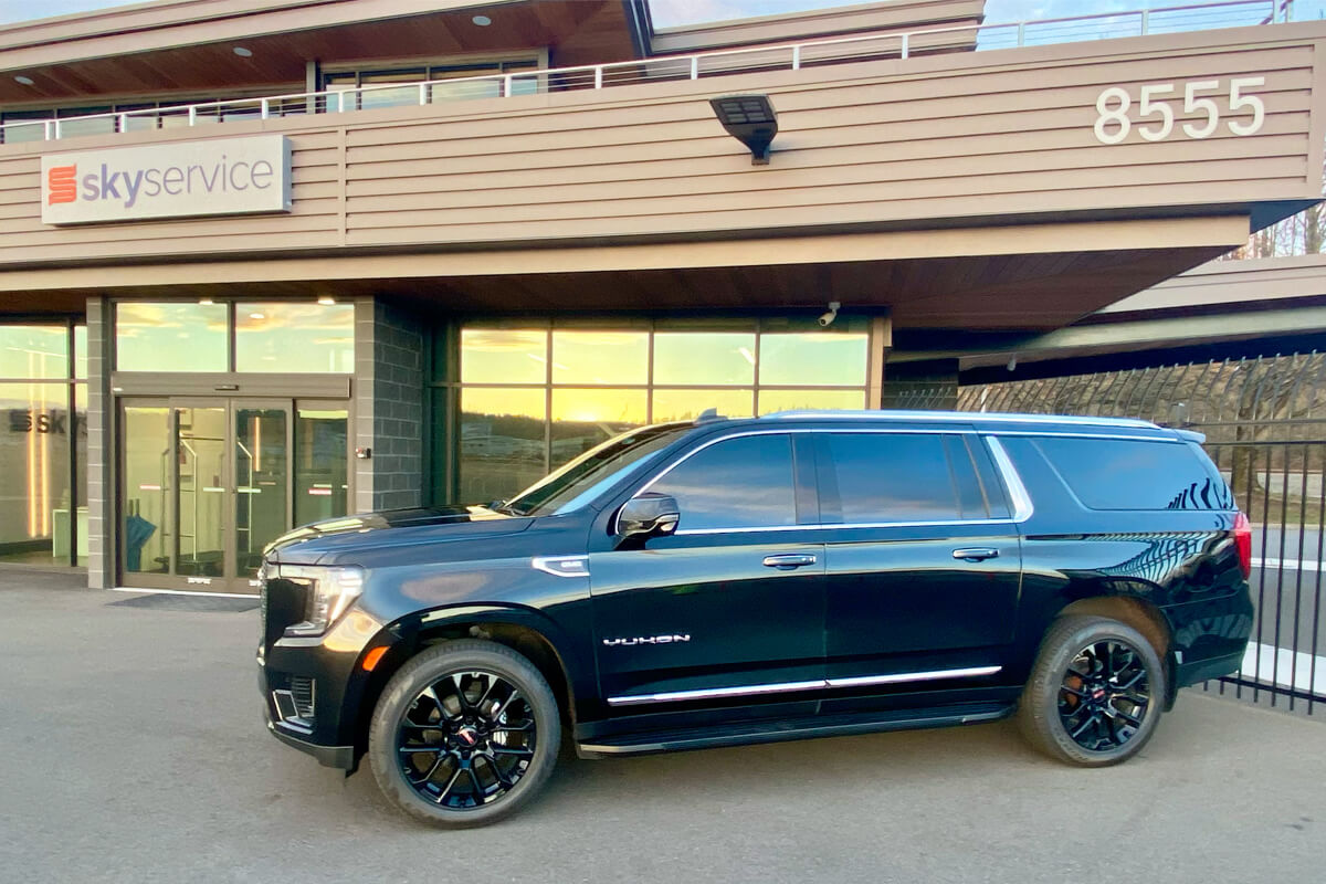 Black GMC Yukon parked outside the Skyservice FBO entrance in Seattle for private aviation pickup service