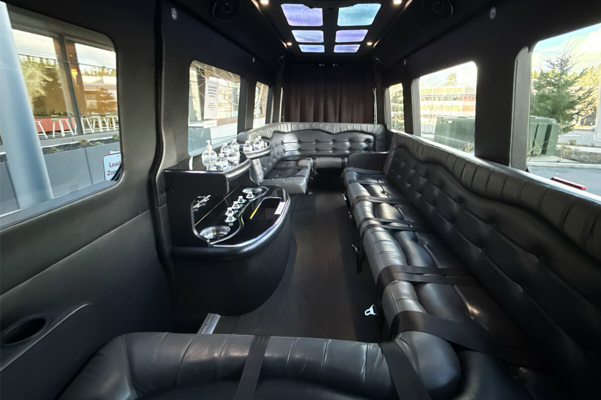 Interior of a black party bus with wraparound leather seating for group event transportation