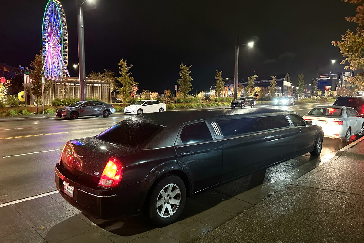 Black stretch limousine parked near the Seattle waterfront and Great Wheel at night