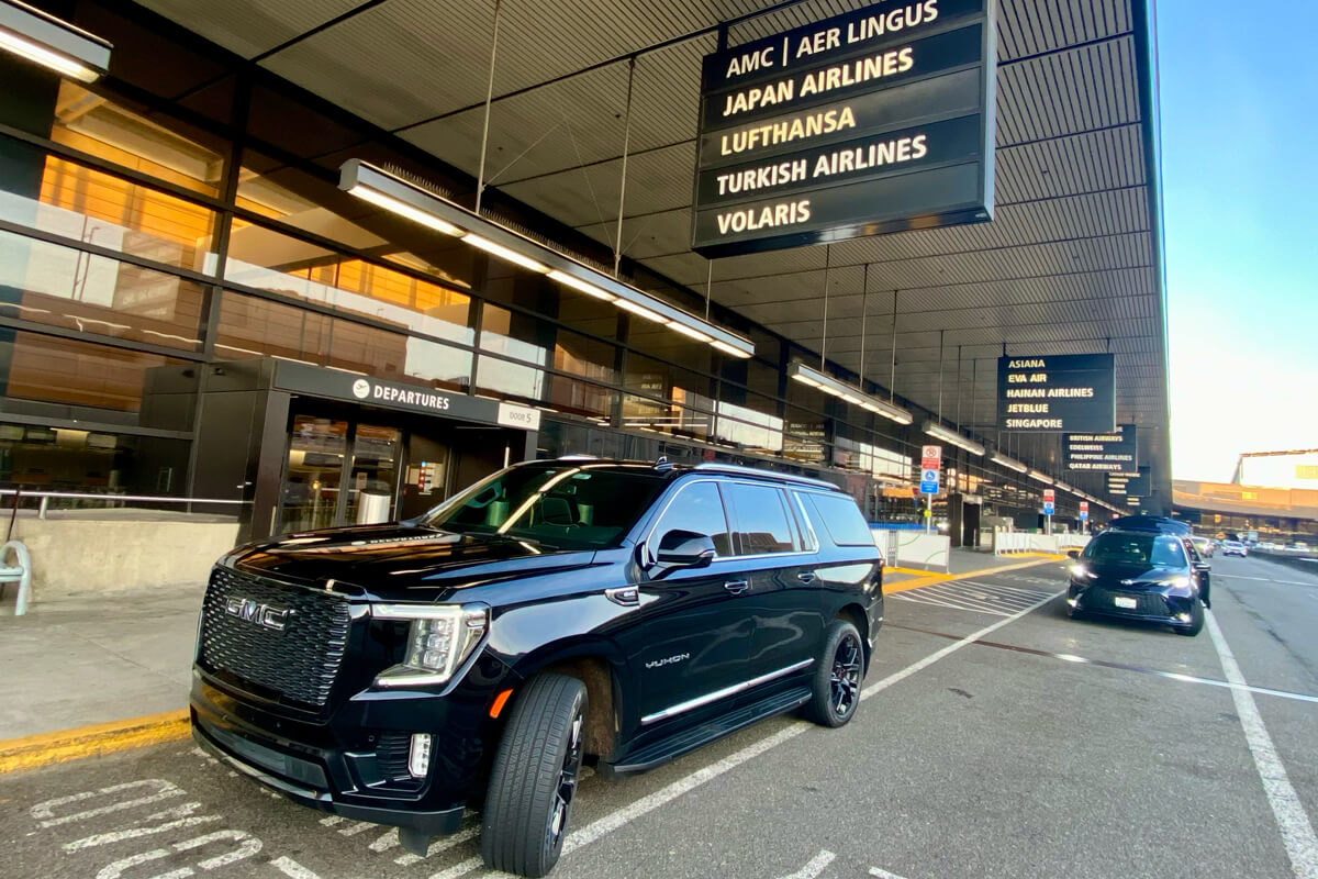 Black SUV waiting at the SEA Airport departures curb for a private airport transfer.