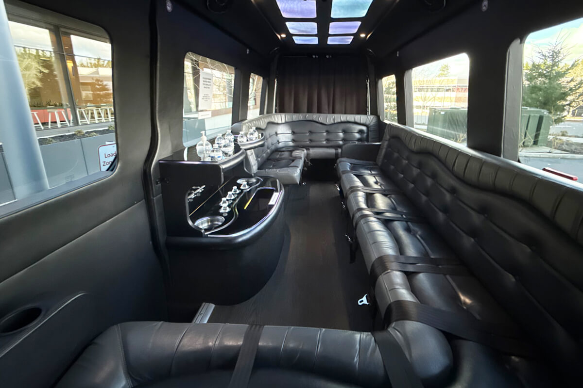 Party bus interior with black leather lounge seating and bar area for Seattle event transportation