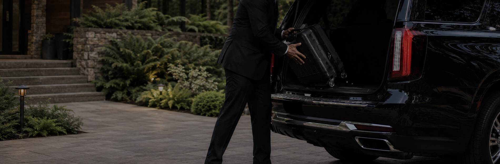 Chauffeur loading luggage into a black SUV for private Des Moines limo service