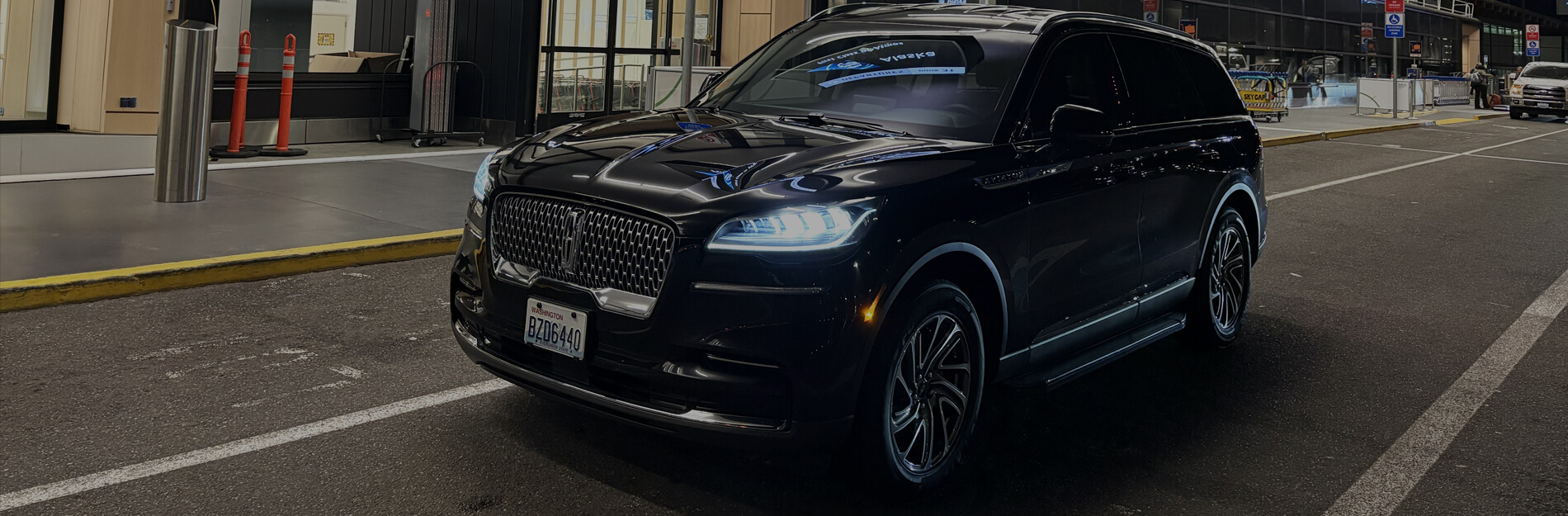 Black luxury SUV parked curbside at SeaTac Airport for a private airport pickup