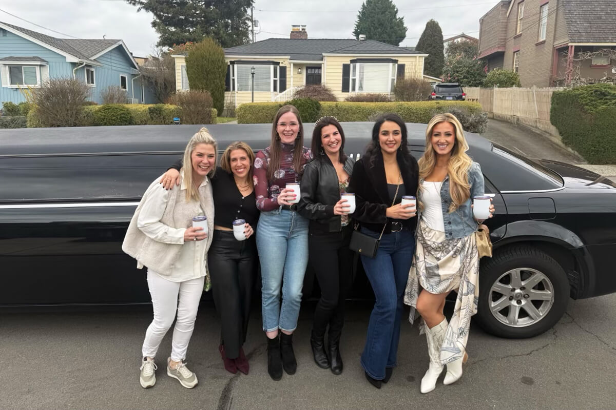 Group of women standing beside a black stretch limousine before an outing