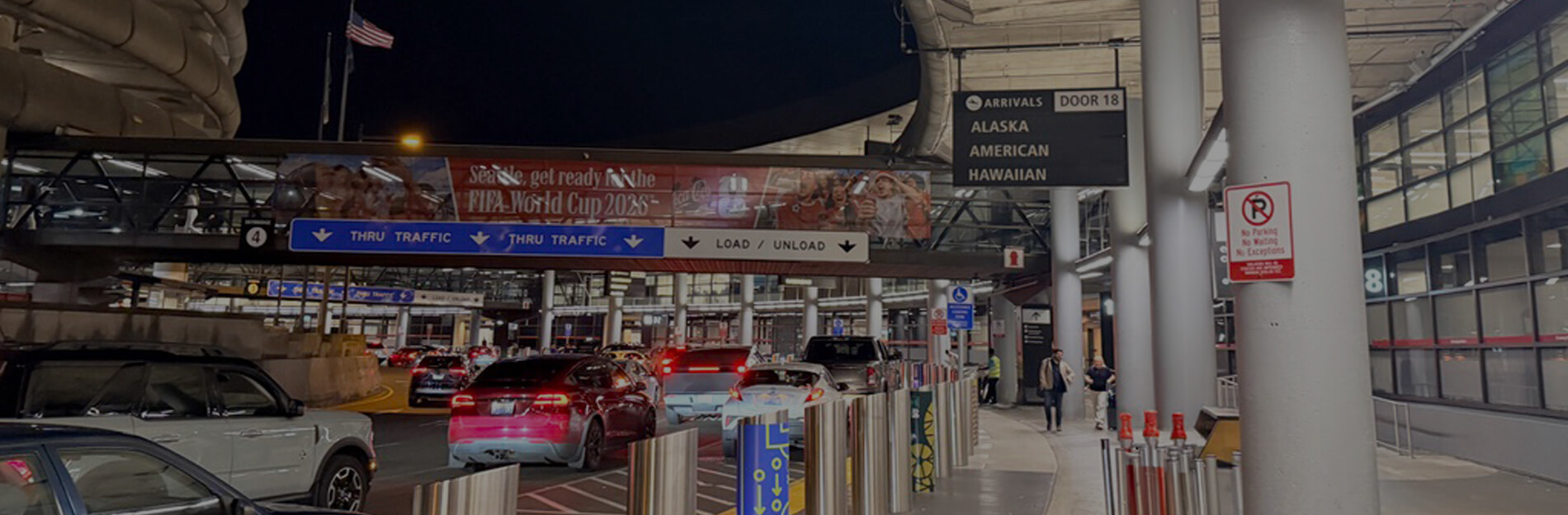 SEA Airport arrivals curb at night with vehicles lined up near Door 18