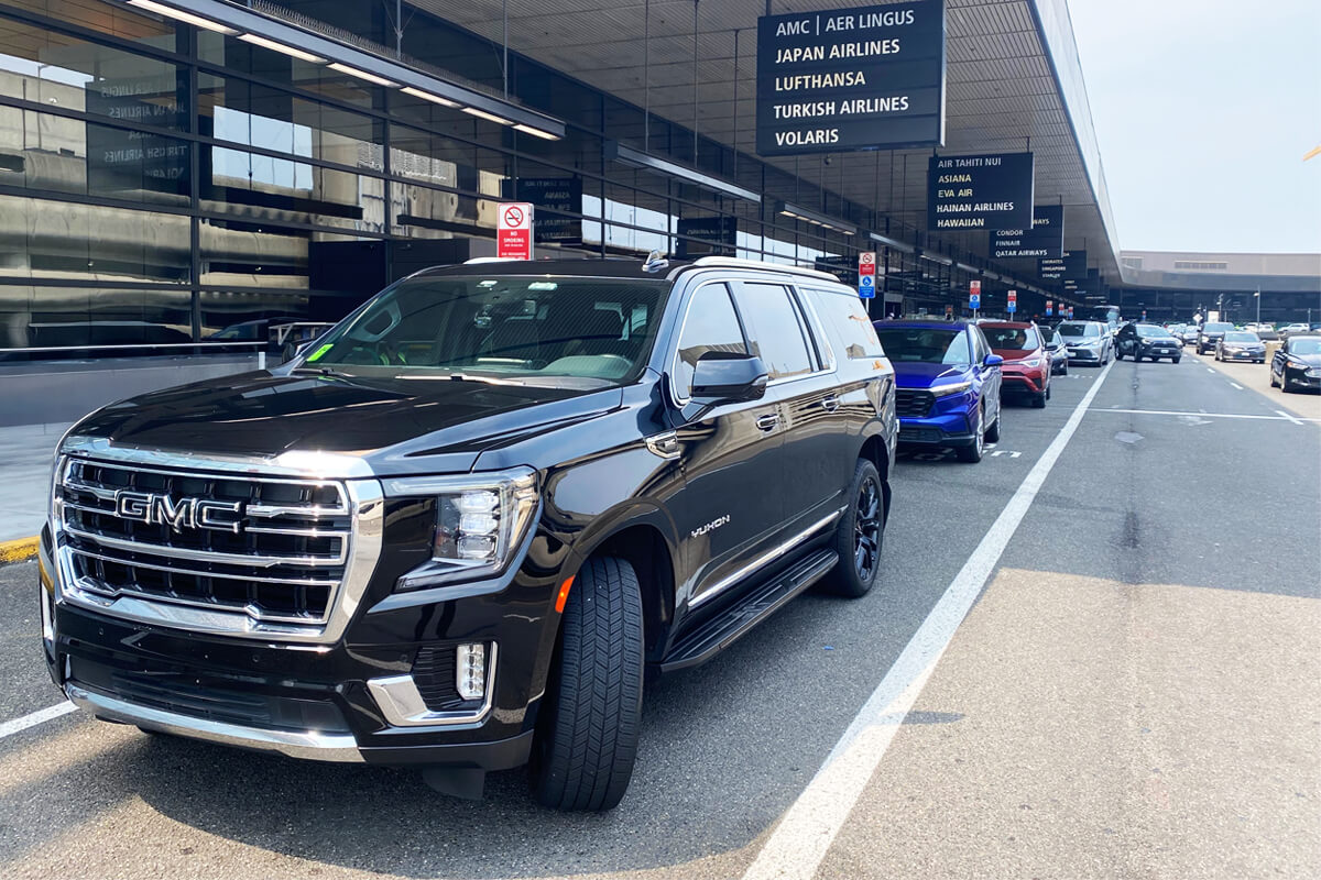 Black GMC Yukon at the SEA Airport curb for passenger pickup