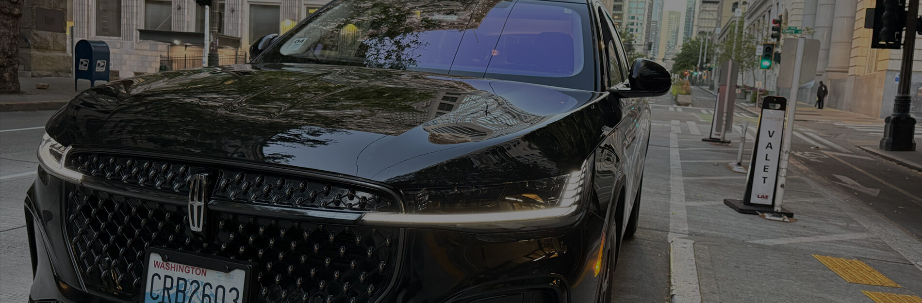 Close-up of a black Lincoln SUV parked beside a valet stand in downtown Seattle.
