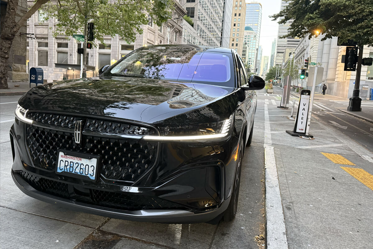 Black Lincoln SUV parked curbside on a downtown Seattle street lined with office buildings.
